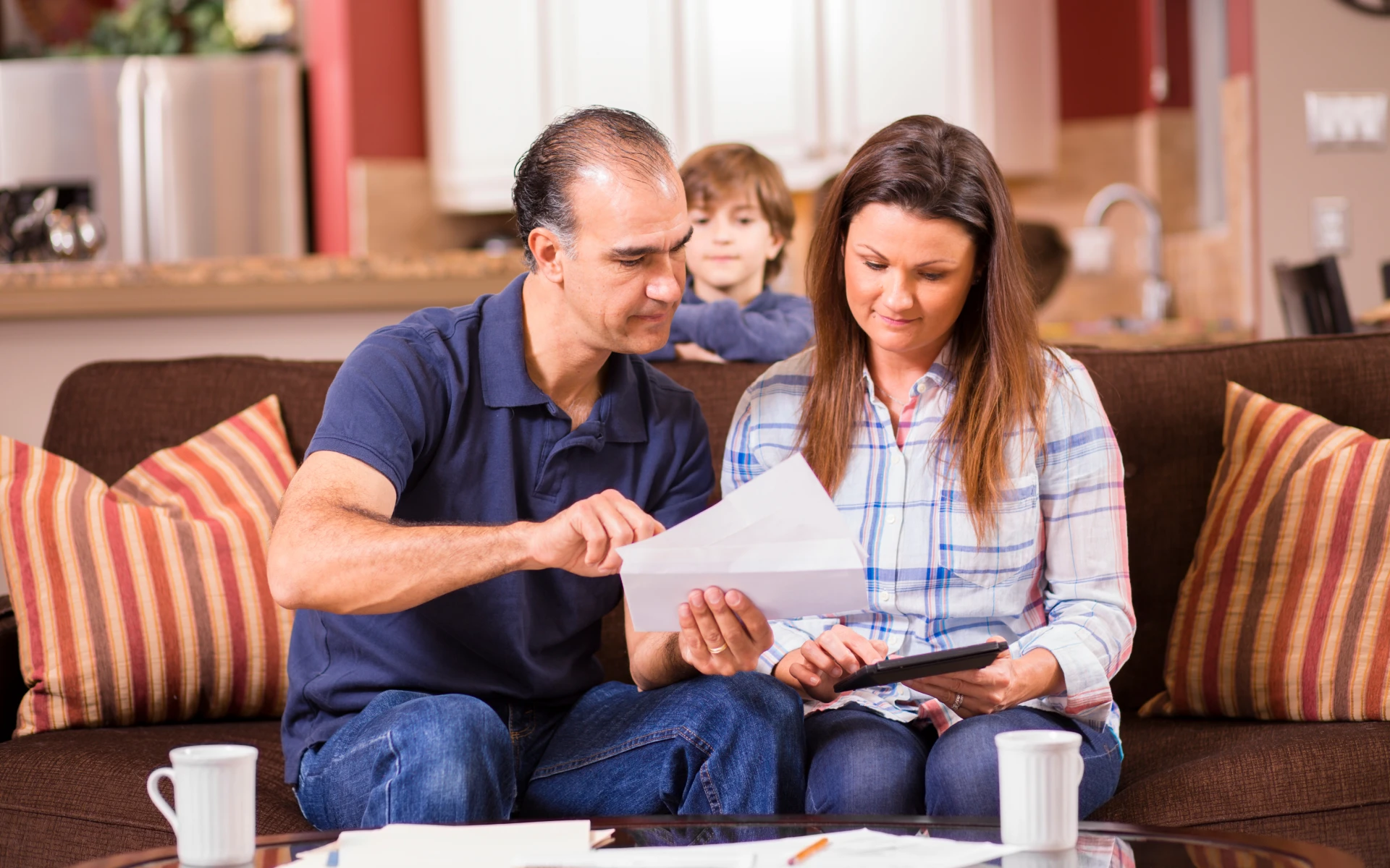 Parents managing finances with child nearby